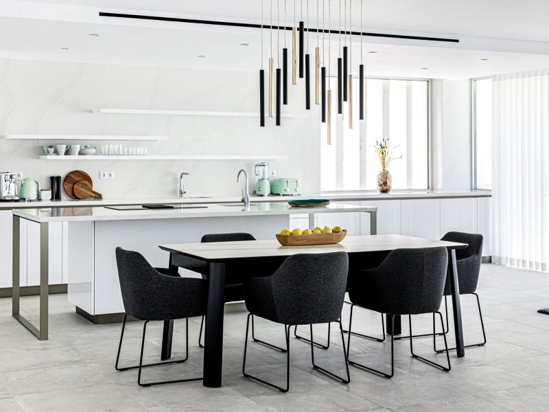 Modern white interior kitchen with brass and black abstract ceiling pendant lighting focal point